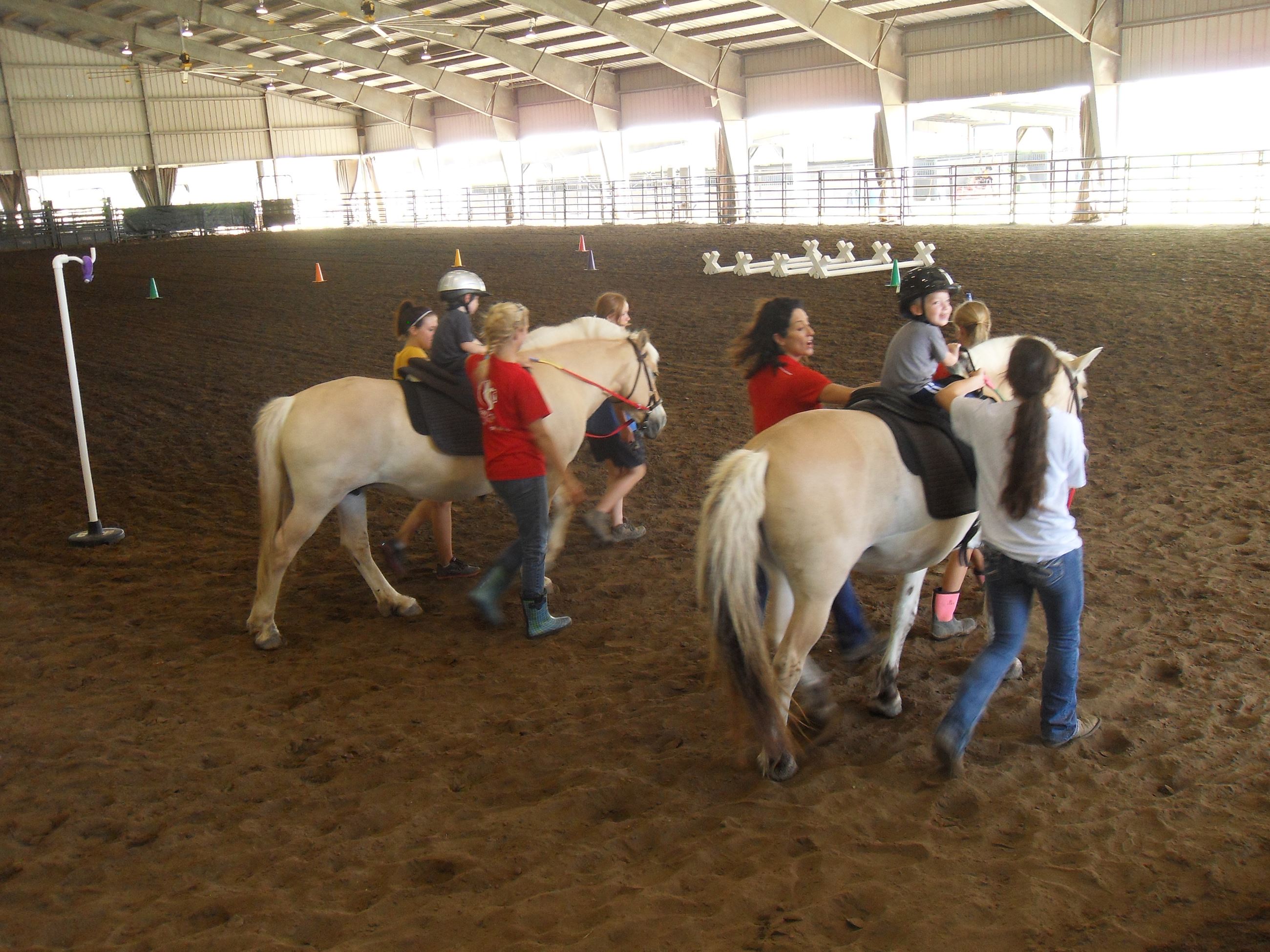 Horses walking around the arena with children riding them