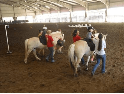 Children riding horses with the help of GaitWay employees